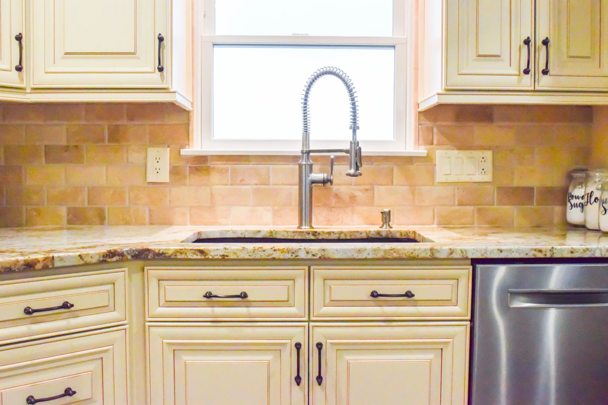 Kitchen completed by BKG Design in Baldwin, PA, with cream cabinets and a travertine backsplash