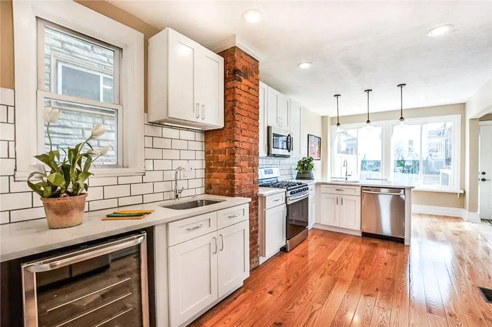 Kitchen completed by BKG Design in Wexford, PA, with white shaker cabinets and an exposed brick chimney