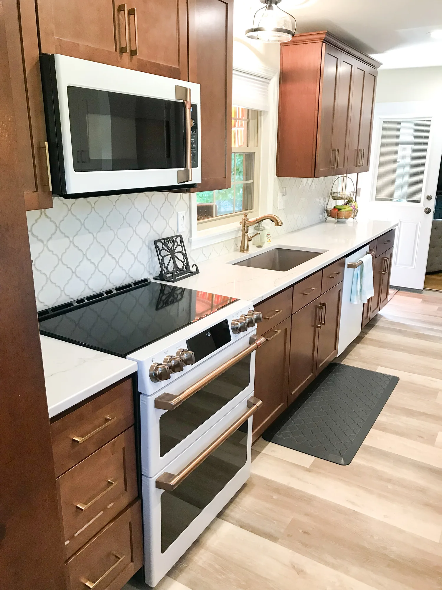 Kitchen completed by BKG Design with stained wood cabinets, brass pulls and a quartz counter